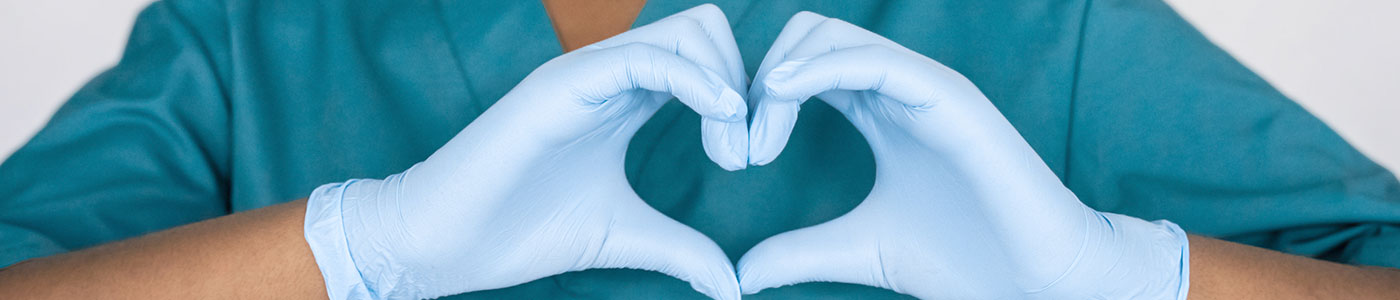 Medical provider forming heart hards while wearing blue latex gloves